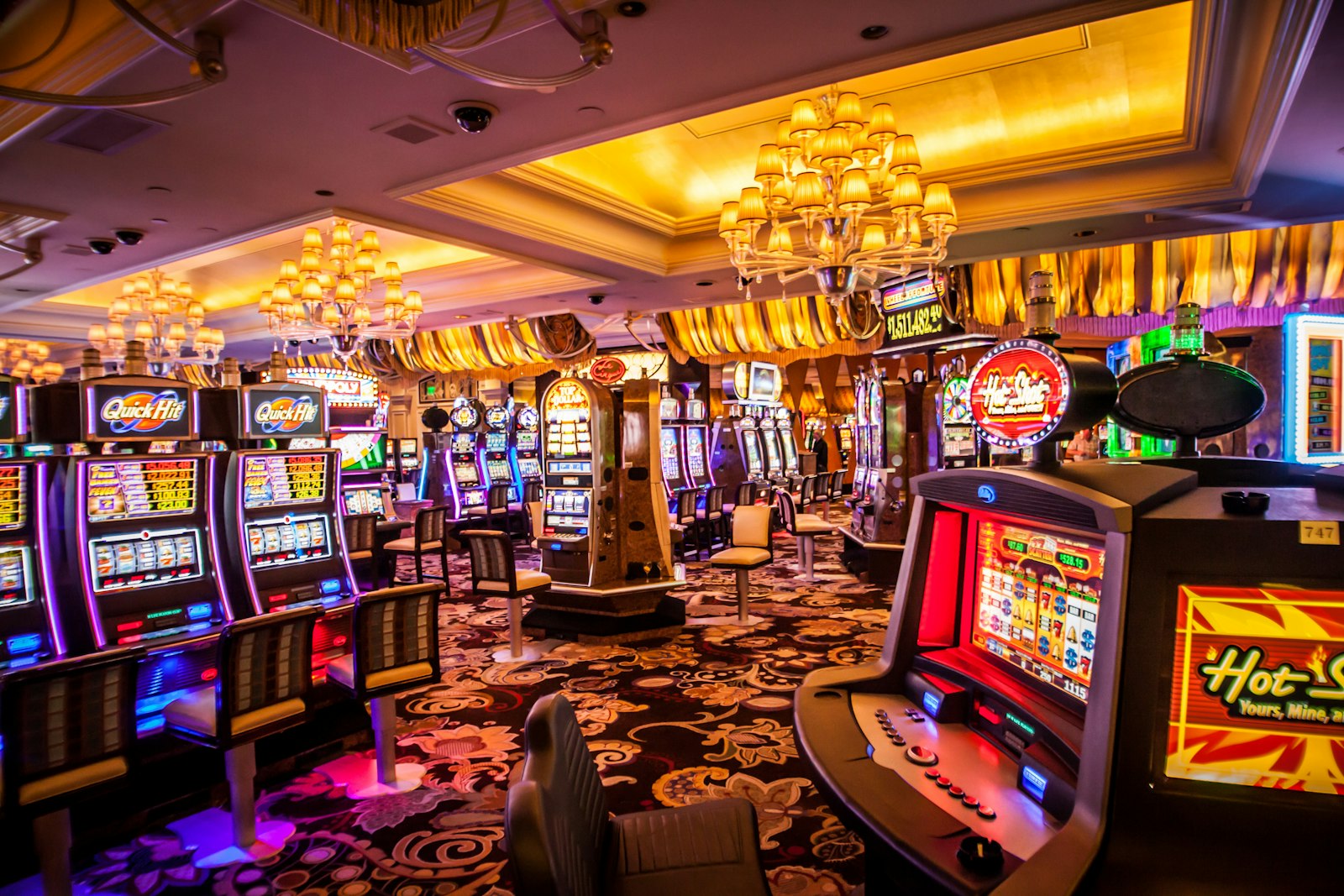 Deretan mesin slot dengan lampu neon di dalam kasino